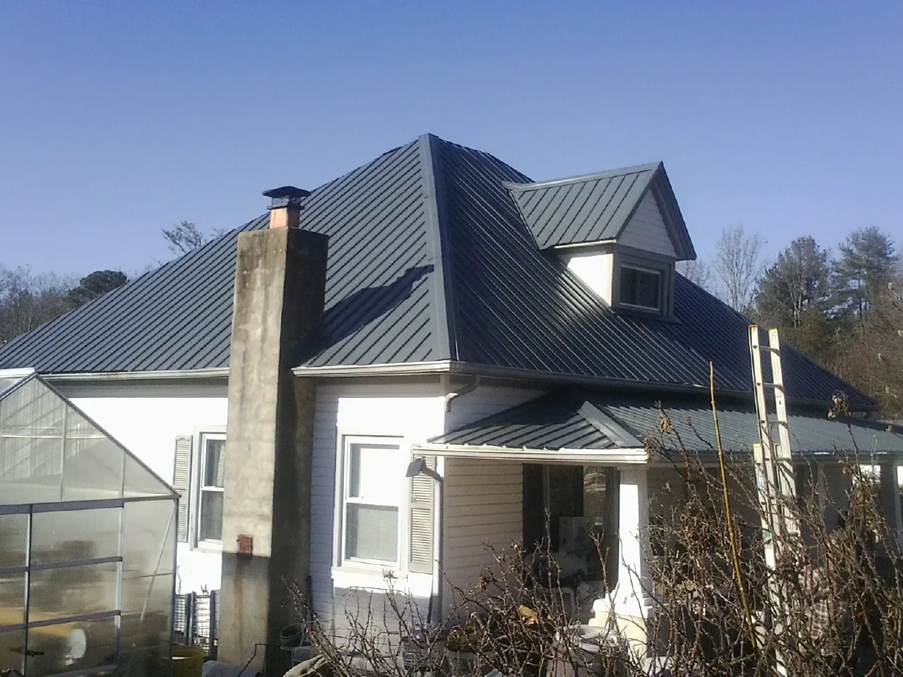 Dark blue standing seam metal roof on a white farmhouse with dormer — Slate & Tile Roof Repair by Roofing Brothers in Frankton