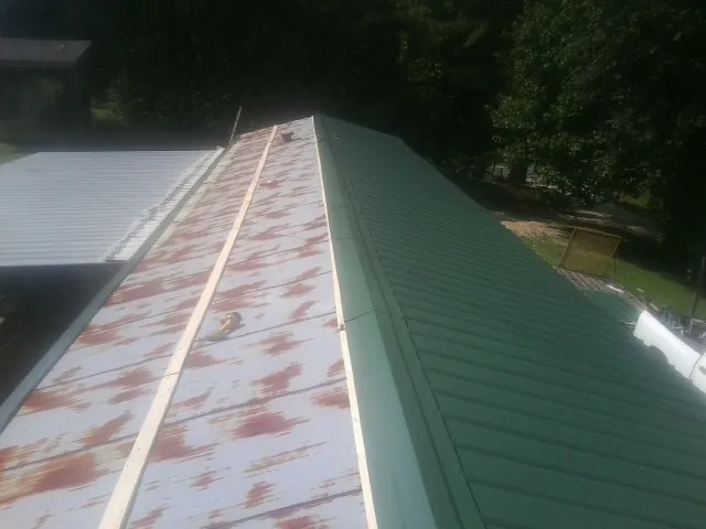 Old rusted panels beside newly installed green metal roofing — Wind Damage Roof Repair by Roofing Brothers in Frankton