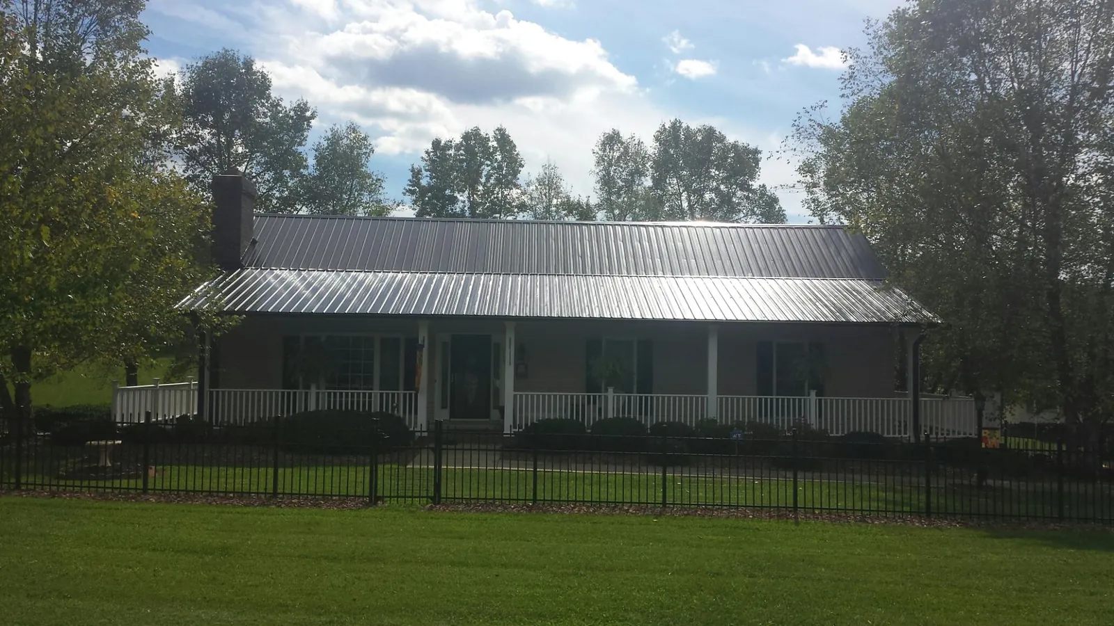 Gray metal roof on a brick ranch with a full width front porch — Gutter Guard Installation work by our crew in Frankton