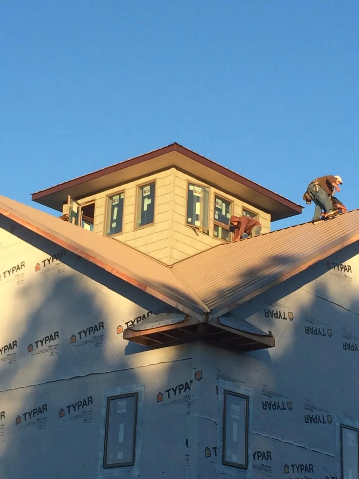 Roofers working around a rooftop cupola on a new metal roof at sunset — Roof Waterproofing in Frankton by Roofing Brothers